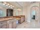 Bathroom featuring double sinks, a large shower stall, and arched doorway to closet at 9909 Moon Valley Pl, Las Vegas, NV 89134