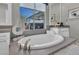 Soaking tub with modern fixtures and a window offering a view of the backyard and water feature at 10096 Amethyst Hills St, Las Vegas, NV 89148
