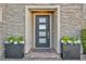 Modern front door with sleek design, surrounded by stone accents and elegant planters at 10096 Amethyst Hills St, Las Vegas, NV 89148
