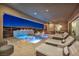 Outdoor living area with a luxurious pool, jacuzzi, lounge seating, and outdoor kitchen at 10096 Amethyst Hills St, Las Vegas, NV 89148