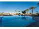 Sparkling community pool with palm trees and lounge seating, reflecting the clear blue sky above at 10096 Amethyst Hills St, Las Vegas, NV 89148