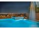 A shimmering pool with a waterfall feature provides a tranquil escape against the backdrop of city lights at 10096 Amethyst Hills St, Las Vegas, NV 89148
