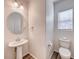 Small bathroom featuring pedestal sink, round mirror, and toilet with window at 10418 Poplar Park, Las Vegas, NV 89166