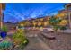 Inviting backyard with pool, fire pit, garden beds, and desert landscaping at dusk at 12356 Grey Dunes Ave, Las Vegas, NV 89138
