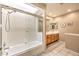 Bright bathroom features a tiled shower/tub combo with glass doors, light colored tile floor and a wooden vanity at 213 N Cimarron Rd, Las Vegas, NV 89145
