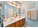 Well-lit bathroom featuring double sinks, wooden vanity, framed mirror, and modern fixtures at 2245 Saint Paul Way, Las Vegas, NV 89104