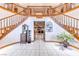 A grand two-story foyer with a double staircase, white tile flooring, and a view into the Gathering room with fireplace at 241 E Country Club Dr, Henderson, NV 89015