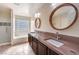 Modern bathroom with dual sinks, glass-block window, and tiled shower at 2653 Rimbaud St, Henderson, NV 89044