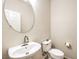 Simple half bath with a pedestal sink, round mirror, and standard toilet at 2653 Rimbaud St, Henderson, NV 89044