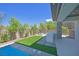 Inviting backyard featuring a pool, artificial grass, and outdoor kitchen area for entertaining guests at 34 Vintage Canyon St, Las Vegas, NV 89141