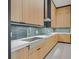 Modern kitchen featuring a stainless steel sink, light wood cabinetry, and sleek countertops and backsplash at 34 Vintage Canyon St, Las Vegas, NV 89141
