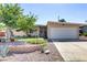 Well-maintained front yard features a tree, flowering plants, rock landscaping and a two-car garage at 5109 Sugarfoot Ave, Las Vegas, NV 89107