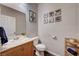 Charming half-bathroom featuring wood-look flooring, oak vanity, and fun artwork at 5453 Brass Hills Ct, Las Vegas, NV 89122