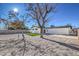 Spacious backyard with gravel, some grass, mature trees, and white exterior of the home at 617 Carpenter Dr, Las Vegas, NV 89107