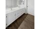 Bathroom featuring double sinks, white cabinets, large mirror, and wood look floors at 6701 Squaw Mountain Dr # 201, Las Vegas, NV 89130