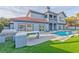 Backyard showcasing an outdoor kitchen, pool, artificial grass and the rear exterior of the home at 8625 Scarsdale Dr, Las Vegas, NV 89117
