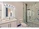 Modern bathroom with a marble-tiled shower, white vanity, and illuminated mirror at 8625 Scarsdale Dr, Las Vegas, NV 89117