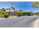 Welcoming entrance to Canyon Fairways with lush landscaping and a guard house, framed by palm trees and clear blue skies at 9325 Canyon Classic Dr, Las Vegas, NV 89144