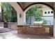 Inviting outdoor kitchen with stone facade, built-in grill, and lush landscaping at 9325 Canyon Classic Dr, Las Vegas, NV 89144