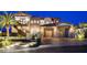 Elegant exterior showcasing stone accents, curved staircase, and three-car garage, complemented by lush landscaping at twilight at 30 Via Tiberius Way, Henderson, NV 89011
