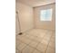 Bright bedroom with tile floors, a large window, a floor lamp, and neutral wall paint at 4480 Annie Oakley Dr, Las Vegas, NV 89121