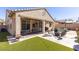 Lush backyard with an artificial turf, stone patio, covered seating area and outdoor kitchen at 472 Cadence View Way, Henderson, NV 89011