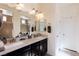 Bright bathroom featuring double sinks, a large mirror, and a separate shower area with neutral colored stone surround at 472 Cadence View Way, Henderson, NV 89011
