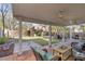 Backyard boasting a covered patio area with seating, lush lawn, and mature trees at 9836 La Vid Ct, Las Vegas, NV 89117