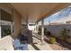 This patio is shaded with chairs, and there is rock landscaping and a brick wall separating other properties at 214 Roxborough St, Henderson, NV 89074