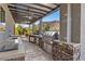 Covered outdoor kitchen area featuring stone accents, bar seating, and grill at 4081 Turquoise Falls St, Las Vegas, NV 89129