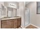 Bathroom with a granite countertop, wooden cabinets, large mirror, and glass shower providing a modern and functional design at 4116 Free Bird Crest Ave, North Las Vegas, NV 89081