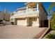 Spacious home featuring a three-car garage and elegant balconies, complemented by a brick driveway at 4384 Grey Spencer Dr, Las Vegas, NV 89141