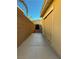 A side yard with a concrete walkway and brick wall, leading to a gate with desert landscaping at 4384 Grey Spencer Dr, Las Vegas, NV 89141