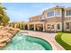 Exterior of house with covered patio, tropical landscaping, waterfall, and putting green at 4542 Grey Spencer Dr, Las Vegas, NV 89141