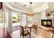 Cozy dining area featuring a fireplace, stylish lighting, and views of the outdoor pool and waterfall at 4542 Grey Spencer Dr, Las Vegas, NV 89141