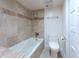 Well-lit bathroom featuring a tub with tiled walls and modern toilet at 5101 Breakers Ln, Las Vegas, NV 89113