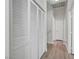 Hallway featuring white louvered closet doors and wood-look floors, leading to additional rooms in the home at 6320 Desert Leaf St # 101, North Las Vegas, NV 89081