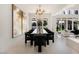 Well-lit dining room with glass table, black chairs, modern light fixture, and backyard views at 8455 Turtle Creek Cir, Las Vegas, NV 89113