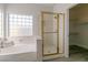 Bright bathroom featuring a soaking tub, glass block window and a glass-enclosed shower with gold trim at 9824 Gallo Dr, Las Vegas, NV 89147