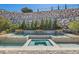 Luxurious pool and spa with a stone retaining wall, mature trees, and a serene backyard setting at 1 Grand Masters Dr, Las Vegas, NV 89141