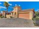 Stucco home featuring a brick driveway, two-car garage, gated courtyard, and desert landscaping at 1150 Calcione Dr, Henderson, NV 89011