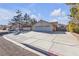 Street view of a desert home featuring mature landscaping and a large driveway at 1709 Guthrie Dr, Las Vegas, NV 89117