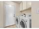 Functional laundry room with a washer and dryer, tile flooring, and storage cabinets at 1709 Guthrie Dr, Las Vegas, NV 89117