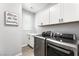 Modern laundry room with gray washer/dryer, white cabinets, and a cute decorative sign at 181 Sierra Alta Pl, Henderson, NV 89015