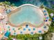 Aerial view of a lagoon style pool with sandy beach, blue umbrellas and palm trees at a residential community at 2504 Cove Rd, Las Vegas, NV 89128