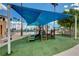 Community playground with a slide and climbing structure, covered by a large sunshade near the lagoon and beach at 2504 Cove Rd, Las Vegas, NV 89128