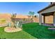 A well-kept backyard with artificial turf, a brick wall, and desert landscaping creates a serene and low-maintenance outdoor space at 26 Lilla Rosa St, Henderson, NV 89011