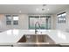 Close up of a large kitchen island, stainless steel sink, quartz counter, and view of the backyard at 26 Lilla Rosa St, Henderson, NV 89011