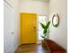 Bright entryway showcasing a yellow front door, wood floors, a plant, and a padded bench at 306 Rodarte St, Henderson, NV 89014