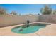 Kidney-shaped pool with a blue decorative pot set on a custom concrete patio and block wall in backyard at 4032 Rustic Oak Ct, North Las Vegas, NV 89032